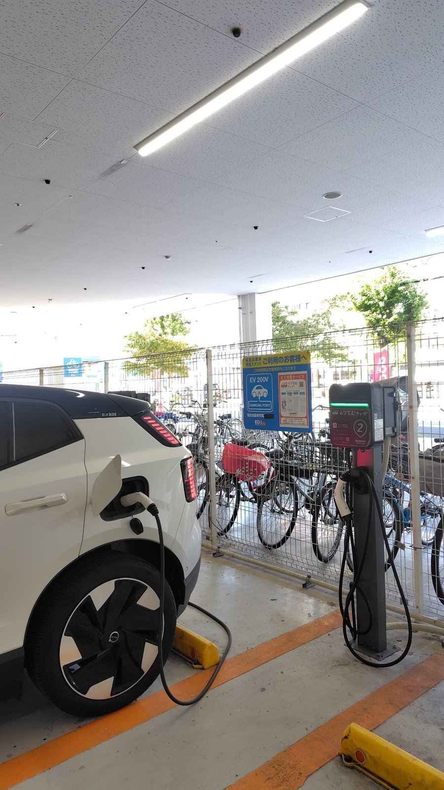 エディオン駐車場の充電器にコネクタをつないで普通充電している様子